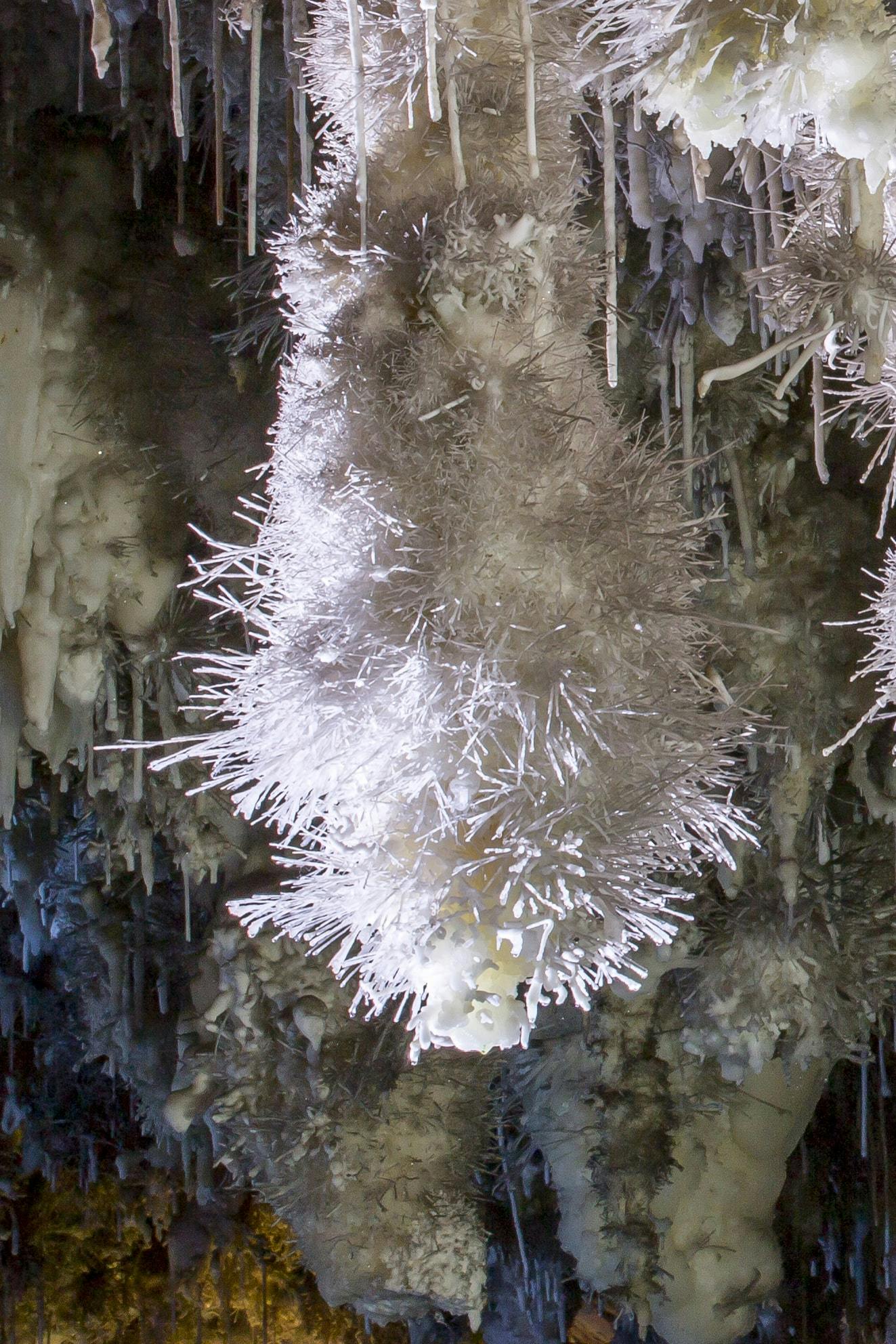 Et hulinteriør, der viser en stor hvid krystallinsk formation med skarpe, nålelignende fremspring, omgivet af andre stalaktitter.