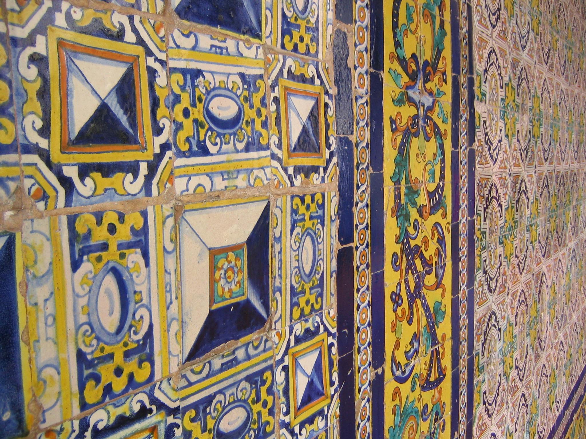 青、黄色、白の複雑なパターンのカラフルなセラミックタイル。幾何学模様を描いたものもあれば、花柄のものもあります。
