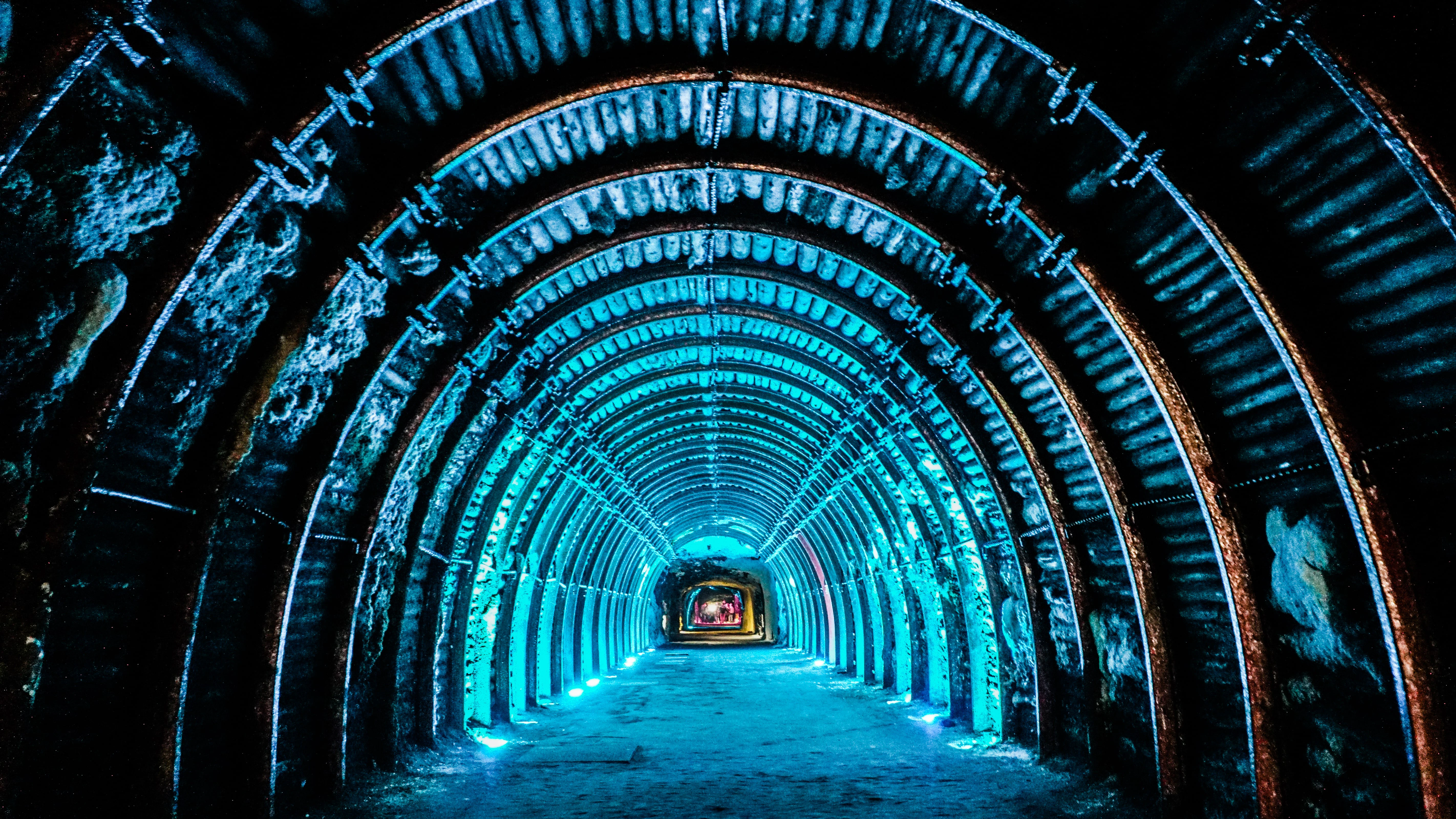 Illuminated tunnel with a series of blue-lit arched ribs extending into the distance, creating a sense of depth and structure.