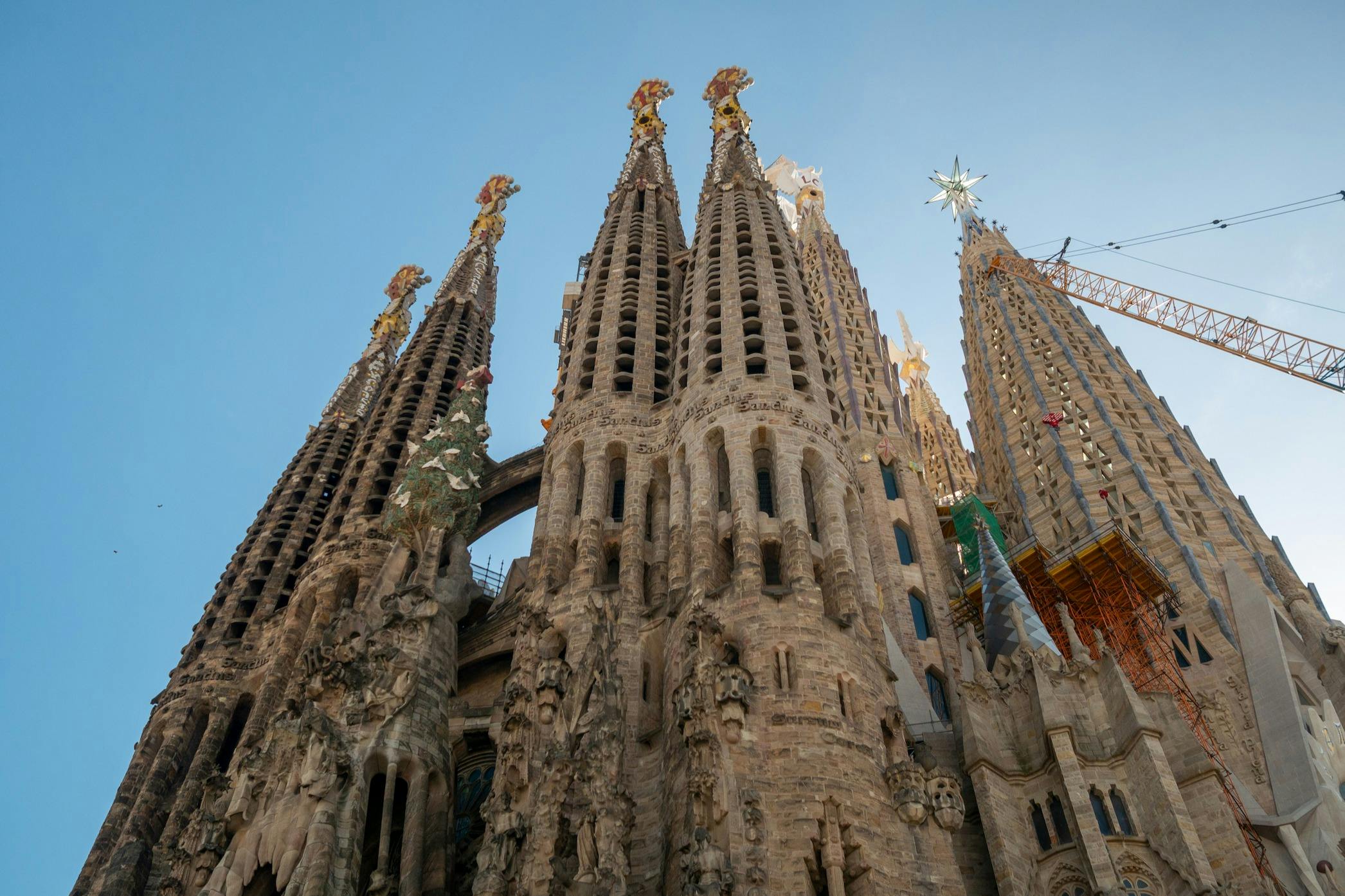 Die kunstvollen Türme der Basilika Sagrada Família in Barcelona vor einem strahlend blauen Himmel.