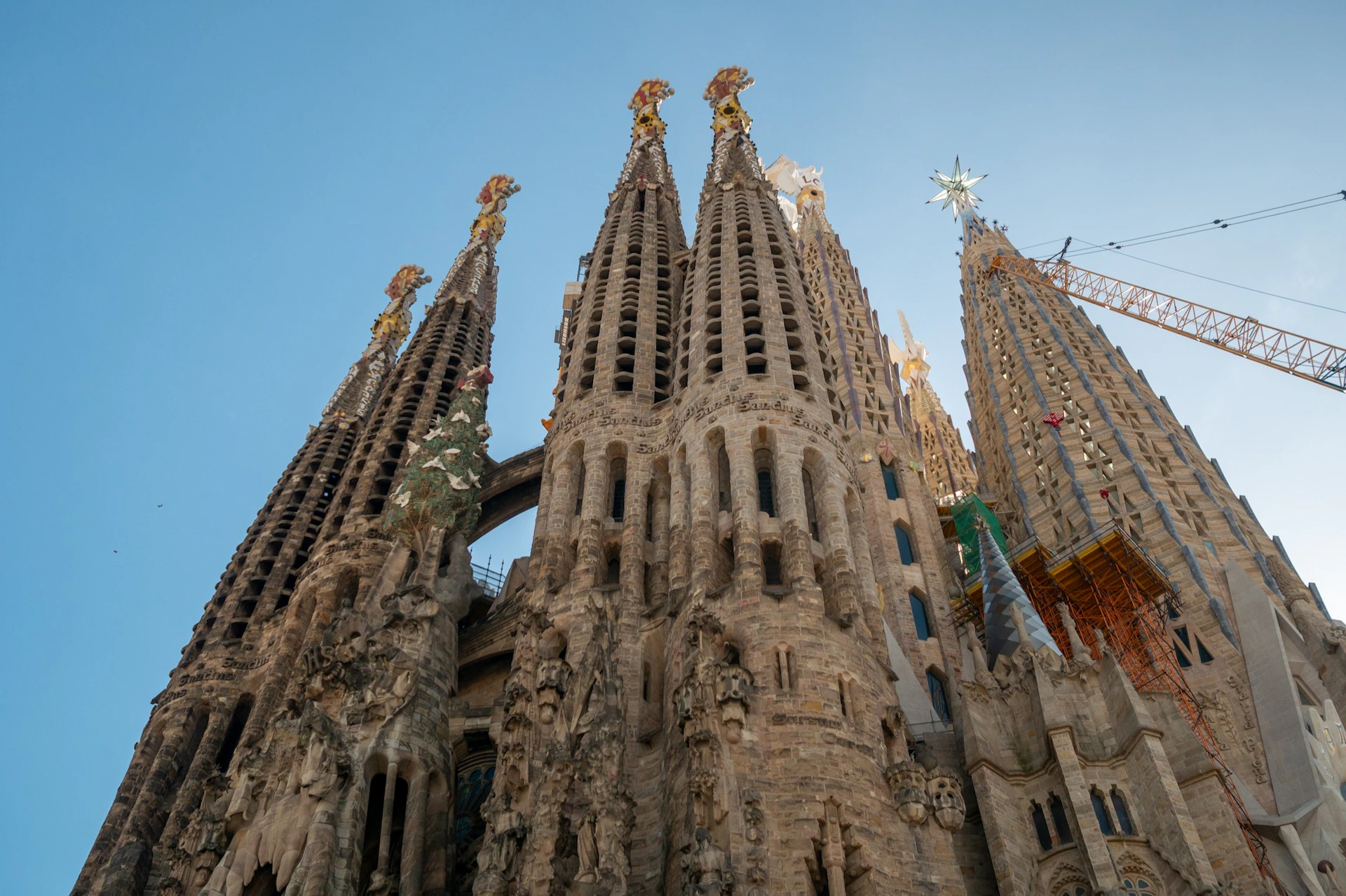 Elaborate spires of the Sagrada Família basilica in Barcelona, against a clear blue sky.
