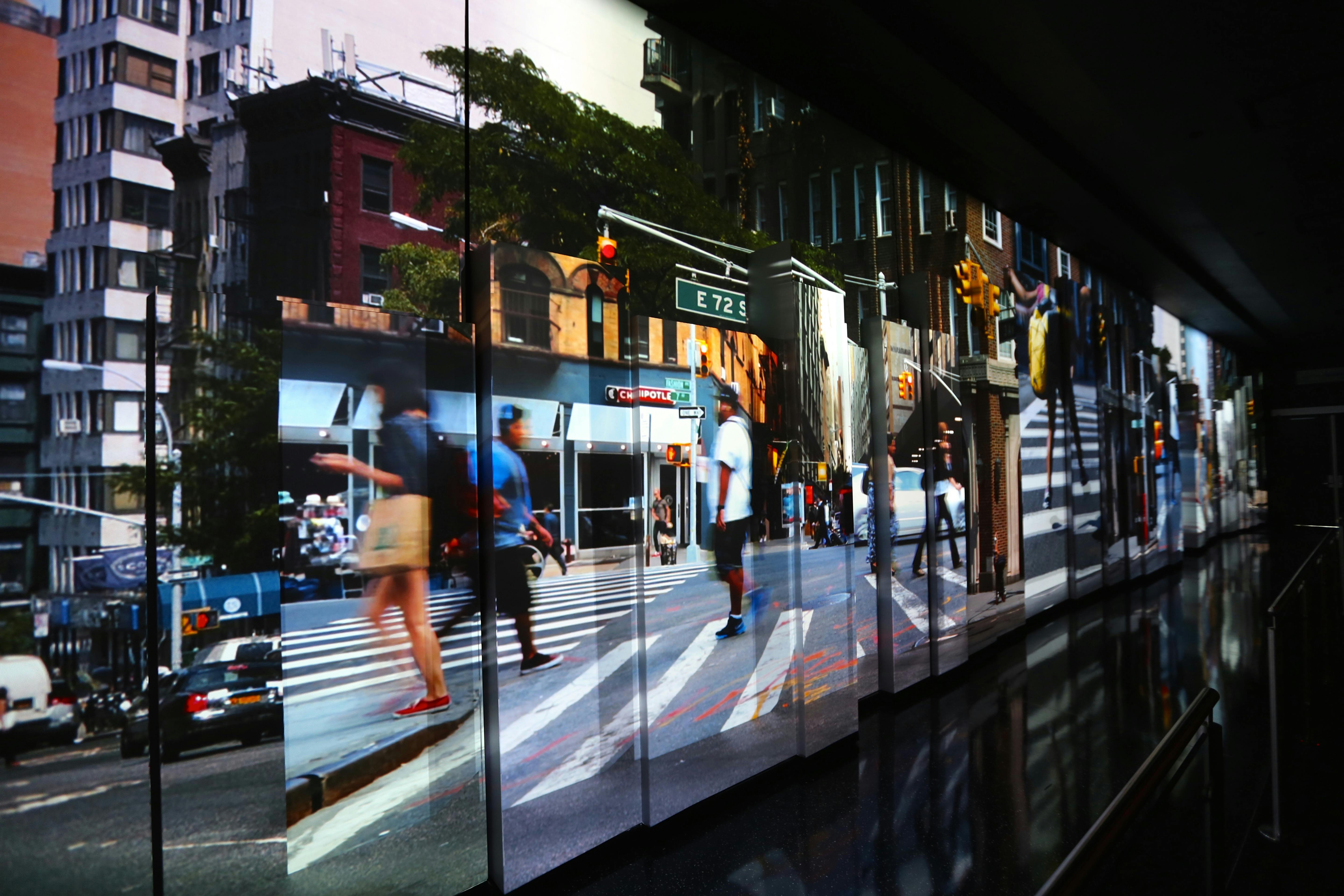 Pessoas a atravessar um cruzamento de uma rua urbana movimentada com movimento desfocado. As passadeiras e os semáforos são visíveis.