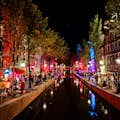 The canals of the Red Light District are illuminated at night.