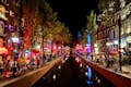 The canals of the Red Light District are illuminated at night.