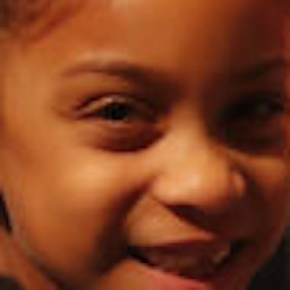 A young girl smiles while exploring a science exhibit with molecular models, wearing a blue shirt and backpack.