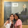 Two guests taking a selfie in front of the painting of Whistler's mother