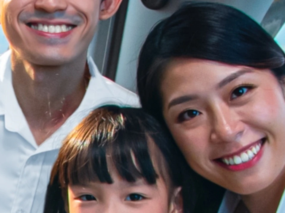 A family of three smiling and seated inside a gondola with a scenic view of water and cityscape visible through the windows.