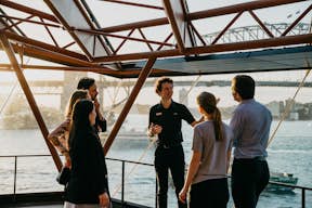 Een tourgroep kijkt uit over de haven en de brug van Sydney terwijl ze worden rondgeleid op hun wandeltocht.