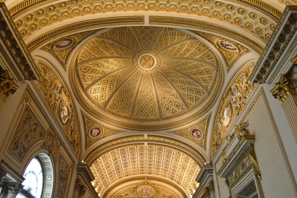 Ornate golden ceiling with intricate patterns and decorative elements in a grand architectural interior.