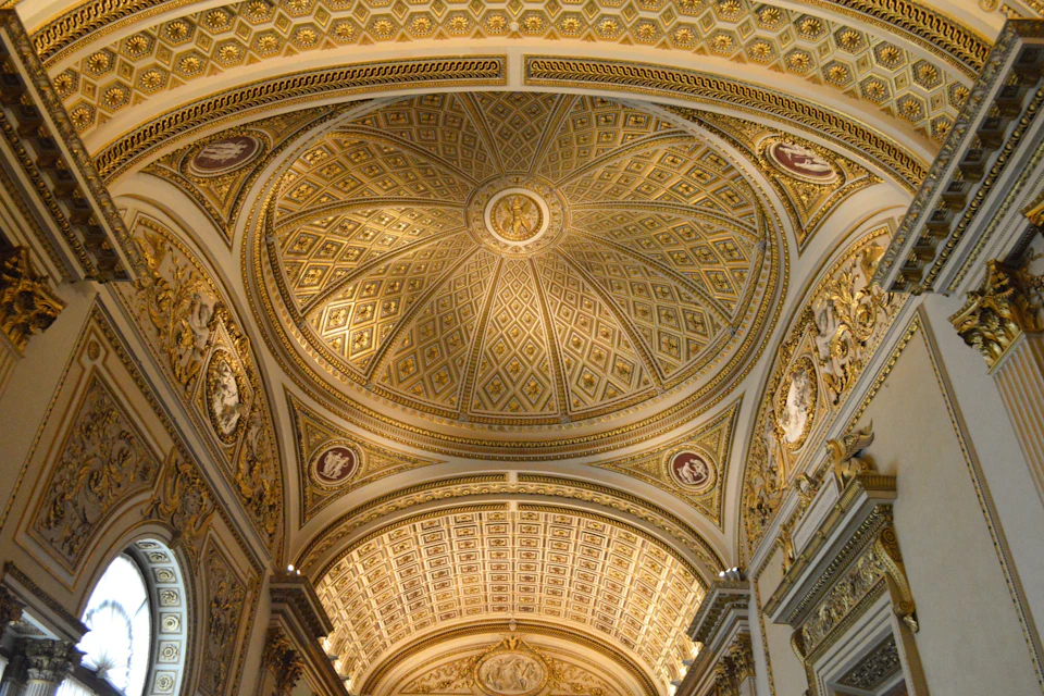 Ornate golden ceiling with intricate patterns and decorative elements in a grand architectural interior.