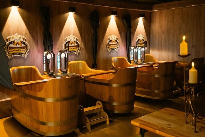 Ένα άνετο μπαρ με ξύλινους θαλάμους σε σχήμα βαρελιού, ο καθένας εξοπλισμένος με τη δική του βρύση μπύρας και διακοσμητικό φωτισμό από πάνω.