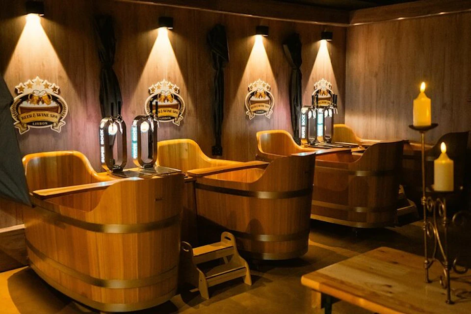 A cozy bar setting with wooden booths shaped like barrels, each equipped with its own beer tap and decorative lighting above.