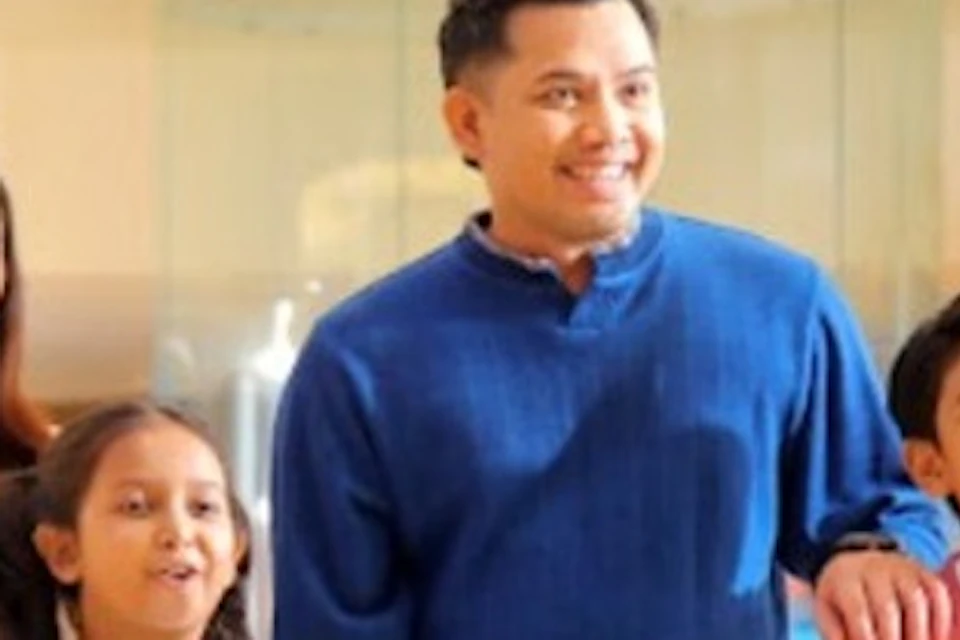 A family of four walking indoors, smiling, with a bright and welcoming environment around them.
