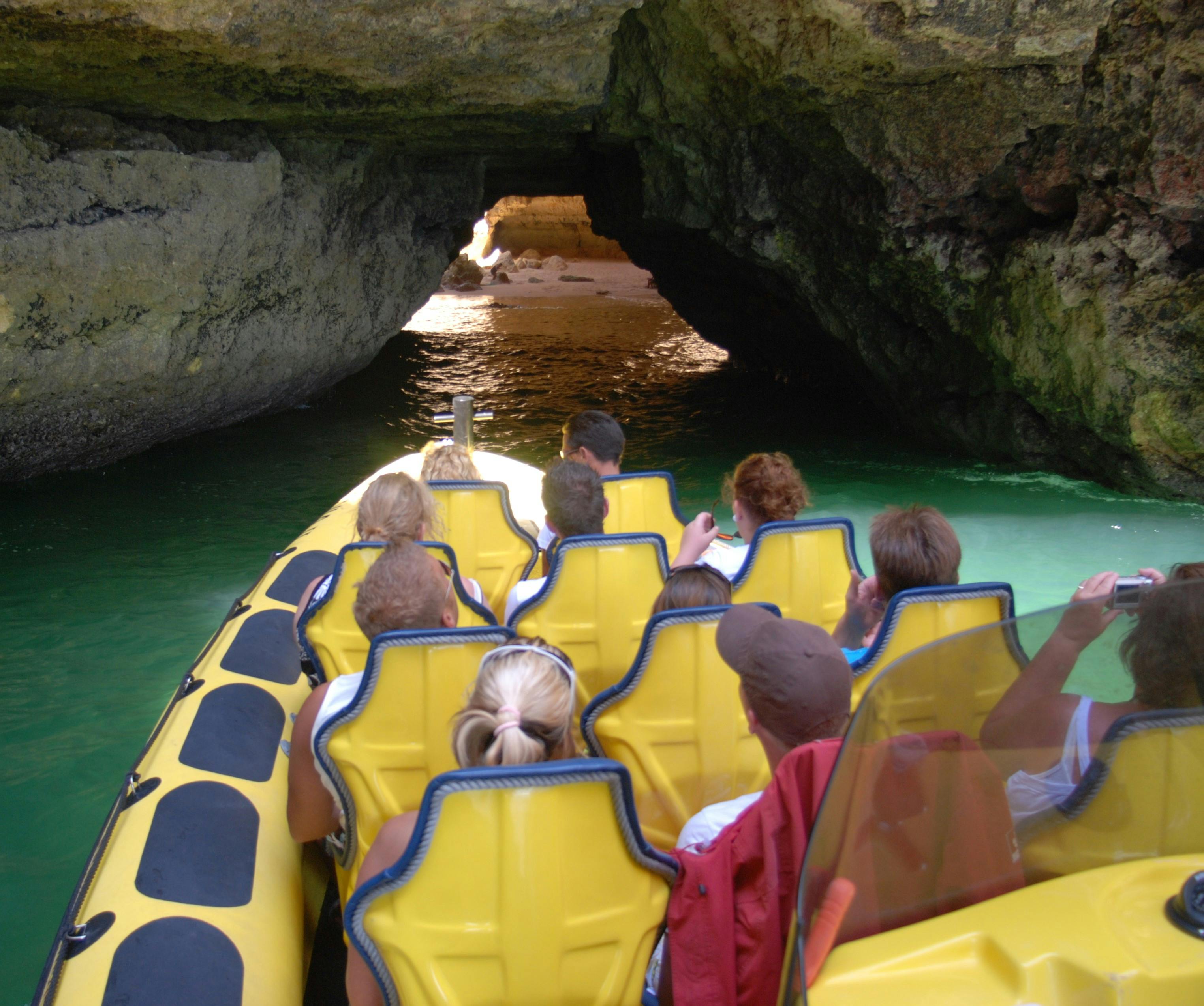 Skupina lidí ve žlutém voru vstupuje do temné jeskyně s vodou.