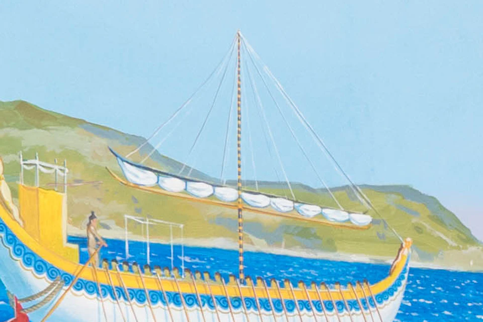 Two mannequins in ancient attire stand on a dock, with a mural of a coastal scene and a ship in the background.
