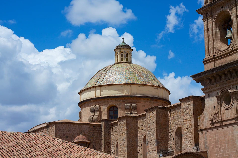 Historic building with a large dome, framed by a bright blue sky with scattered clouds.