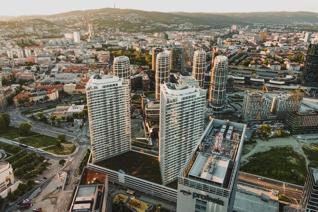 在夕阳下，鸟瞰城市景观，包括多栋高层建筑，融合了现代和旧建筑。