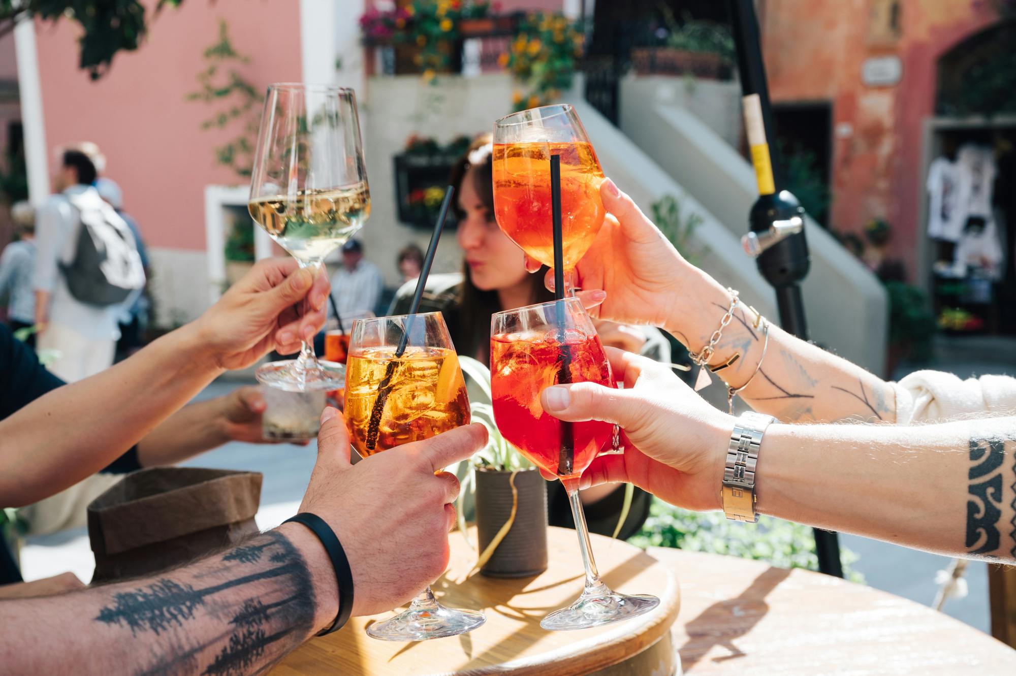 四个人在室外放置植物和花卉，用玻璃杯盛满饮料，包括Aperol烈酒和白葡萄酒。