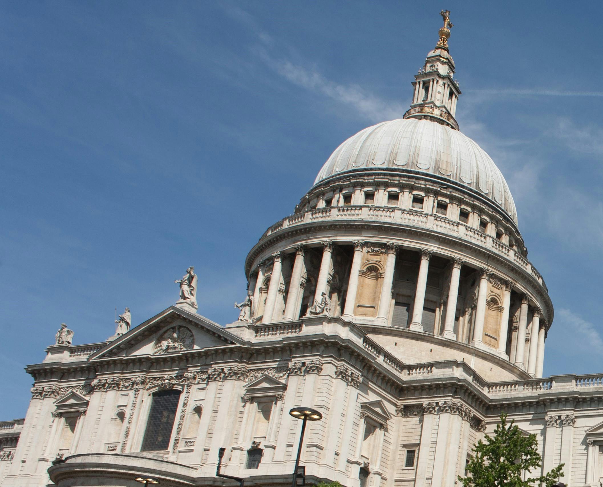 一座历史悠久的大型圆顶建筑，晴朗的蓝天下有柱子和错综复杂的石头细节。