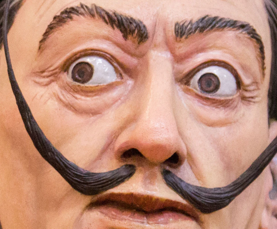 Lifelike statue of a man with a distinct mustache, wearing a red scarf with "Erotic Museum Barcelona" text, and a suit.