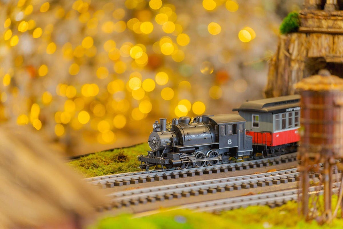 Et modeltog mærket "New York Central" på spor med en sløret baggrund af gule bokeh-lys.