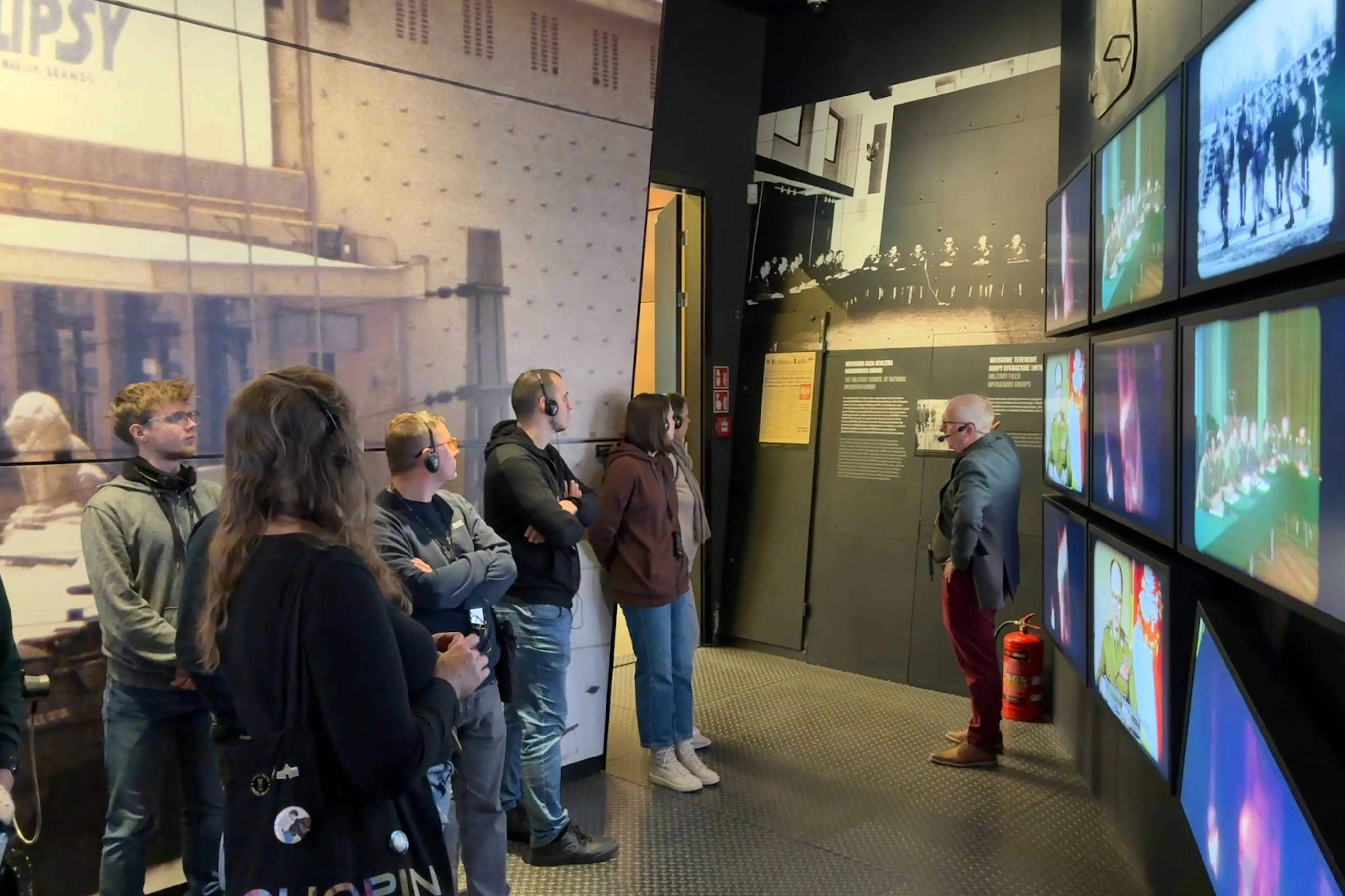 Els visitants en un espai d'exposició del museu amb fotos històriques i exposicions informatives a les parets. Persones amb auriculars.