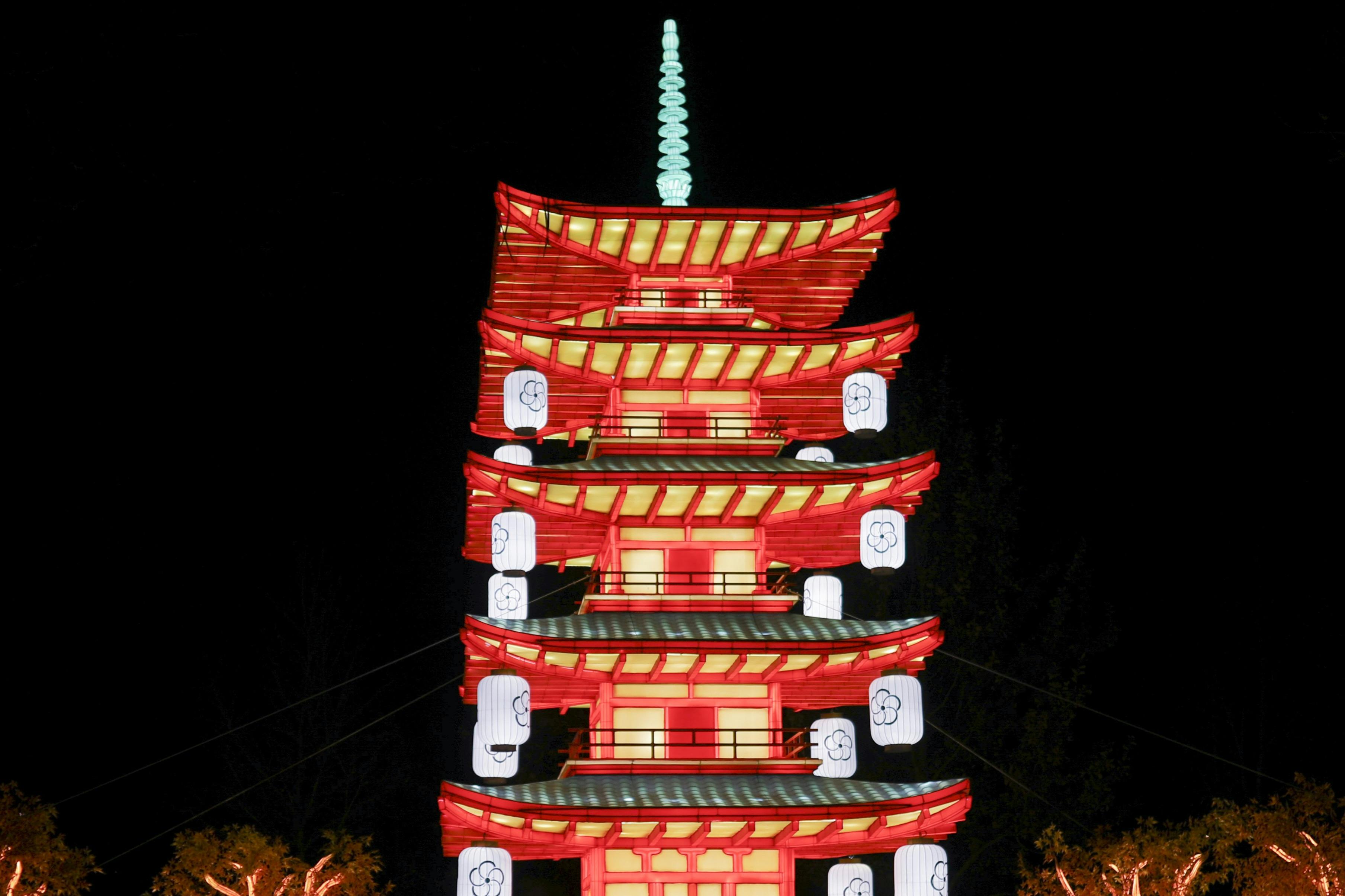 밝은 조명의 여러 층으로 된 빨간색과 노란색 탑으로 밤에는 등불이 걸려 있습니다.