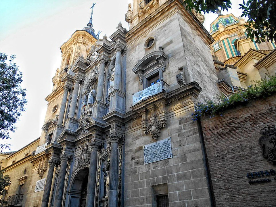 Ornate stone facade of a historic building with statues and intricate architectural details, including columns and decorative elements.