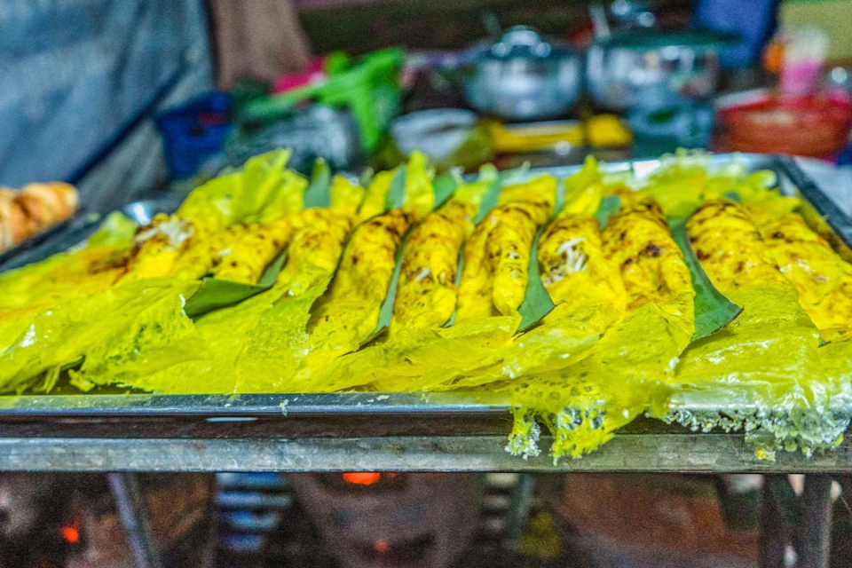 Yellow crispy snacks laid out on a tray with metal pots and kitchen items in the background.