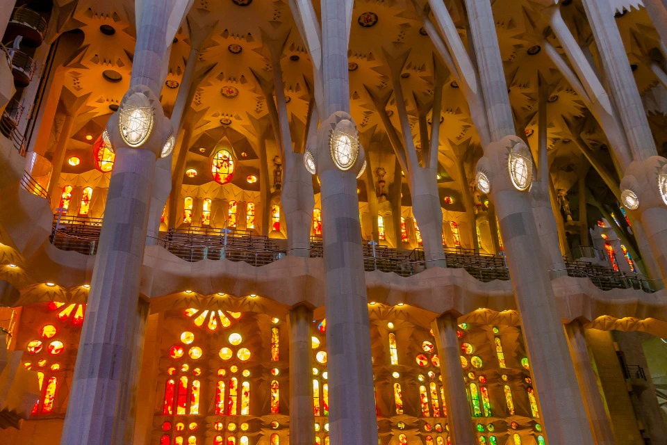 Interior of a cathedral with tall columns, intricate ceiling, and colorful stained glass windows.