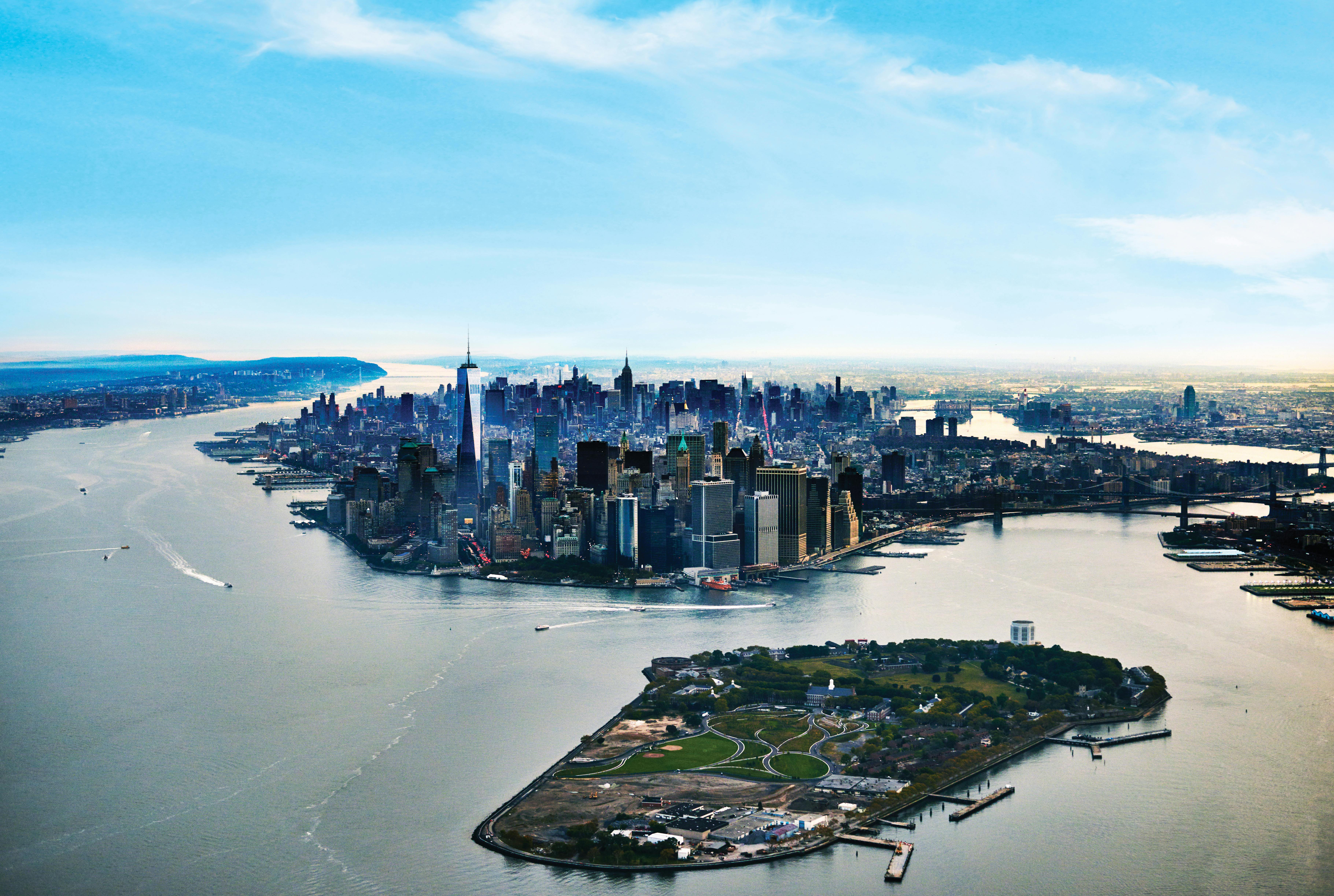 水に囲まれた広大な高層ビルや、前景に緑が広がる島が広がるマンハッタンのスカイラインを眺めることができます。