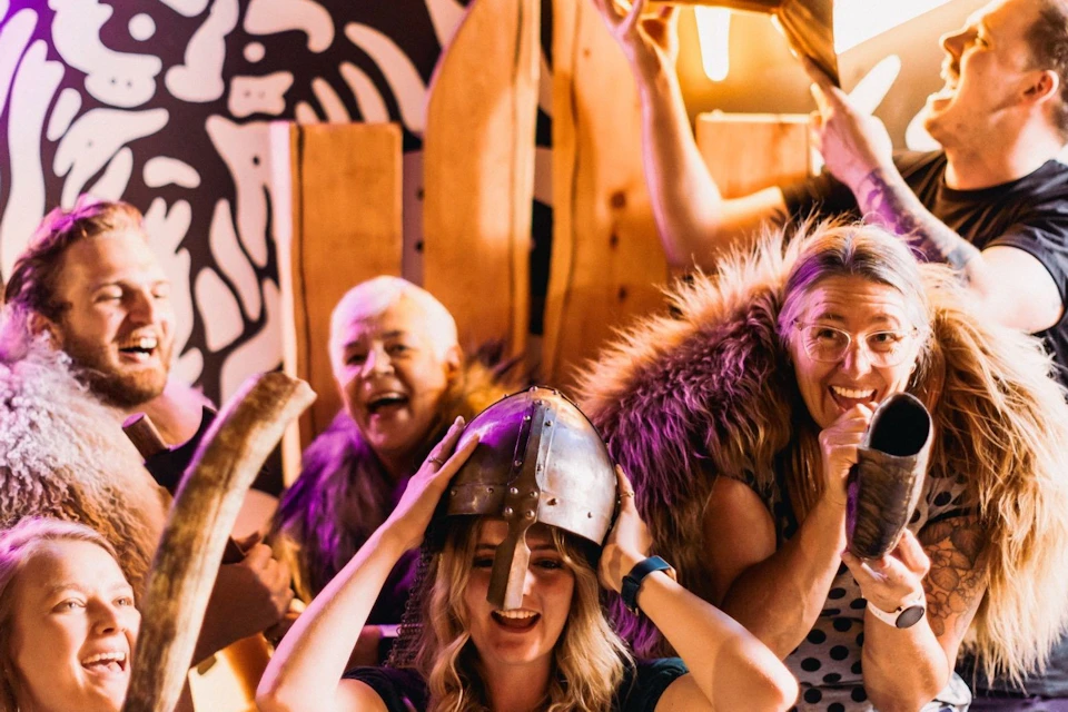 A group of people wearing Viking-themed costumes, holding drinking horns, and posing in a festive environment.