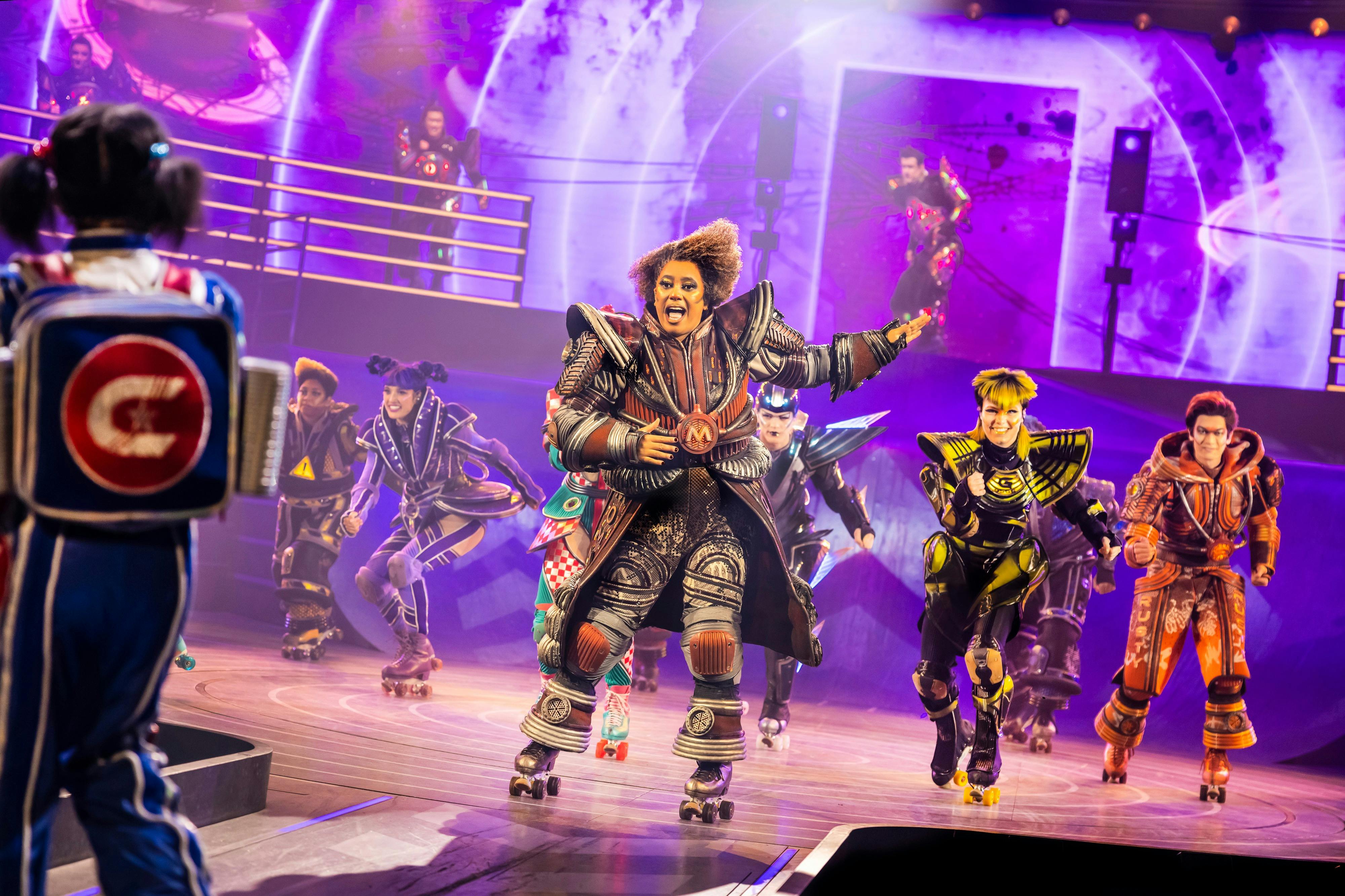 穿着未来服装和溜冰鞋的表演者在明亮的舞台上精力充沛地表演，紫色和蓝色的灯光。