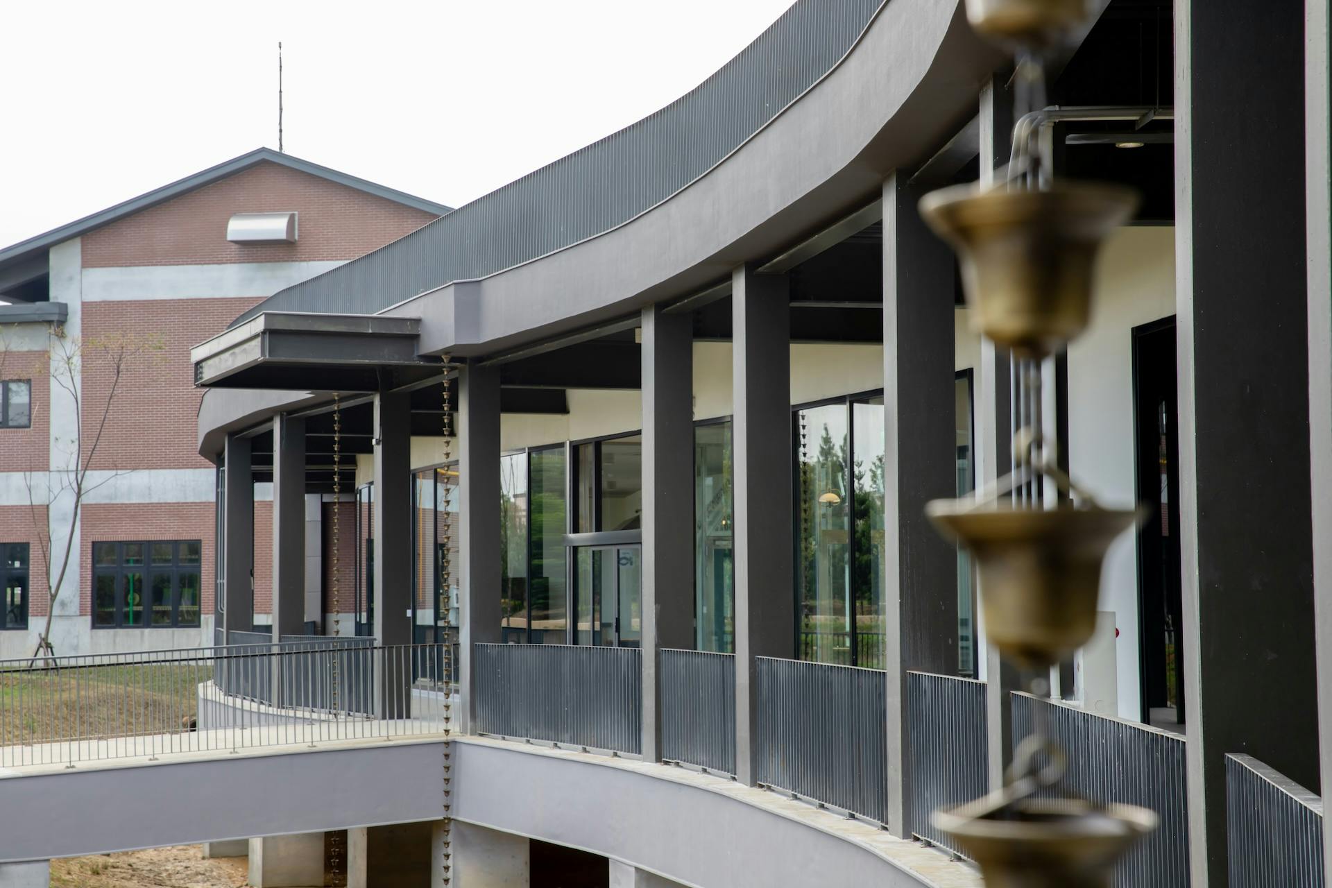 Modern building with curved glass windows and vertical columns, featuring a decorative chain in the foreground.