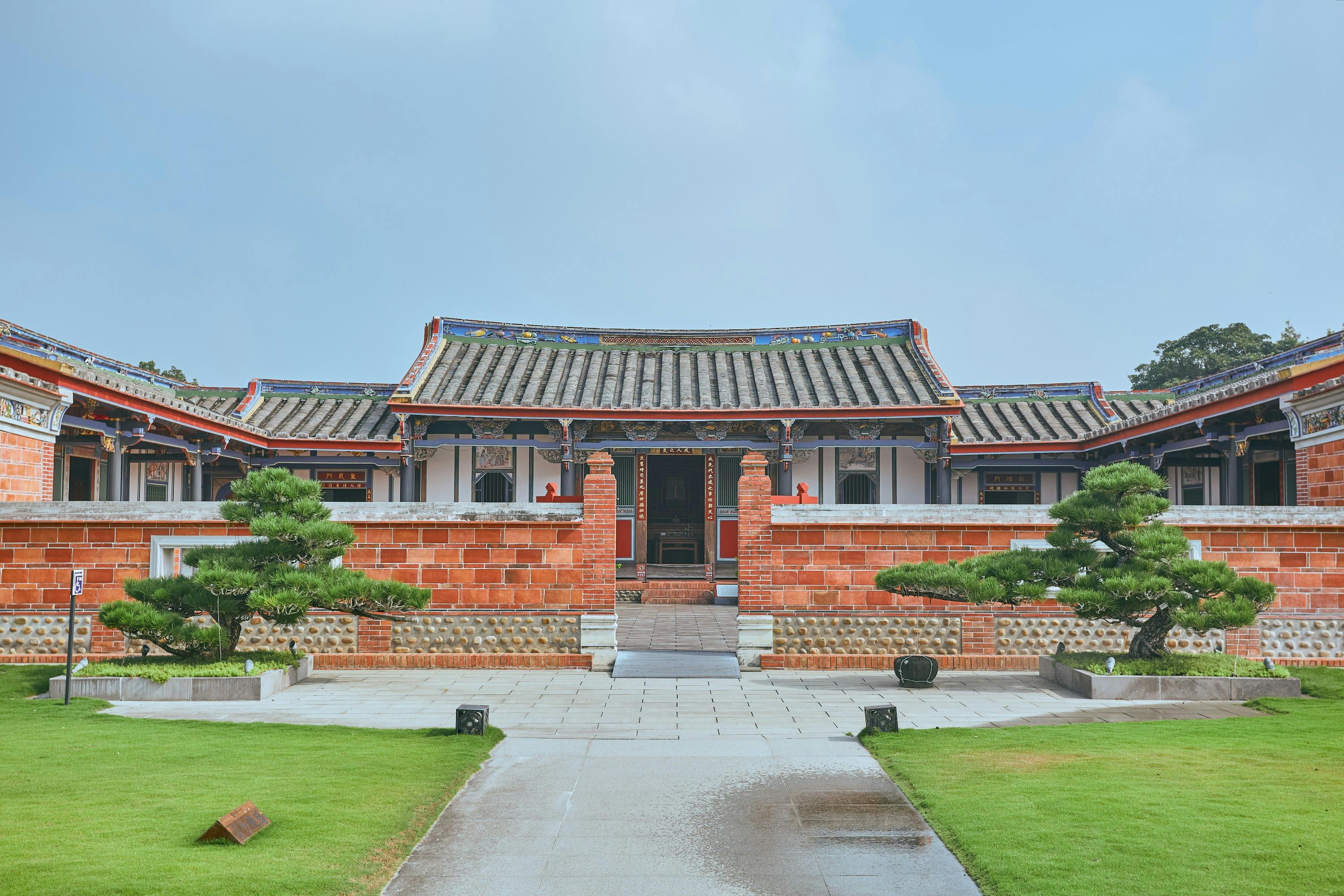 Traditional Chinese-style building with a tiled roof, brick walls, and a courtyard surrounded by greenery.