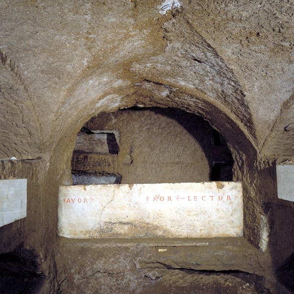 An underground tomb with an arched ceiling and Latin inscriptions on a white marble slab.