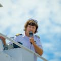 En skæv kaptajn taler ind i en mikrofon, mens han kører båden fra en vingestation