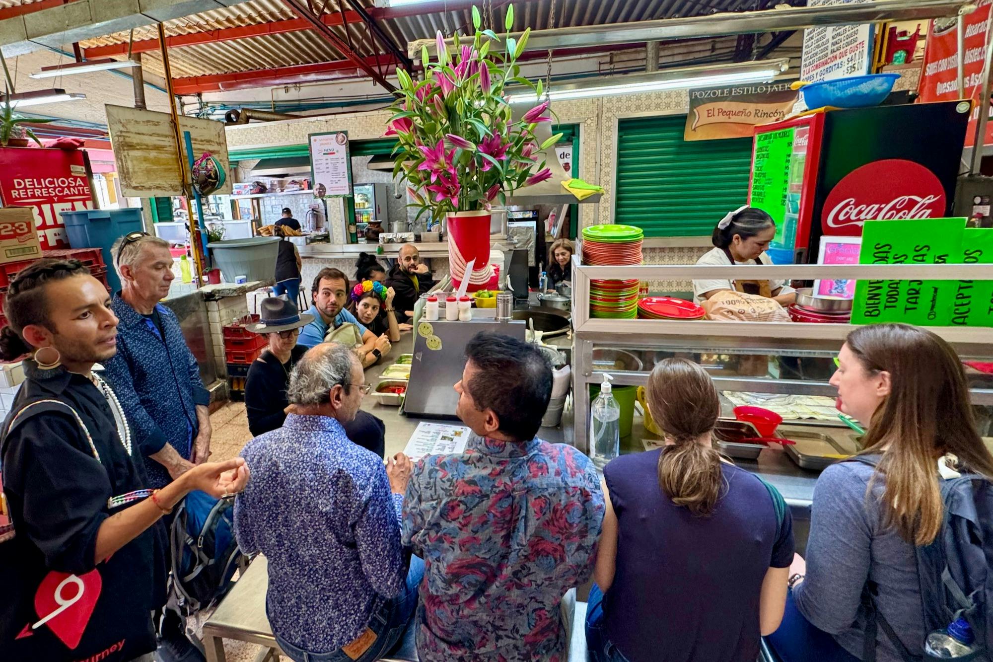 Die Menschen versammelten sich um einen kleinen Essensstand mit bunten Tellern und einer Vase mit Blumen und unterhielten sich.