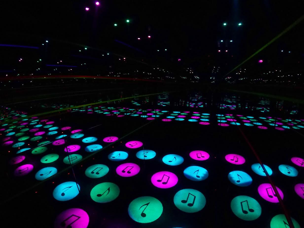 Gloeiende muzieknootpictogrammen in blauw, roze en groen worden weerspiegeld in spiegels en creëren zo een illusie van eindeloze patronen.