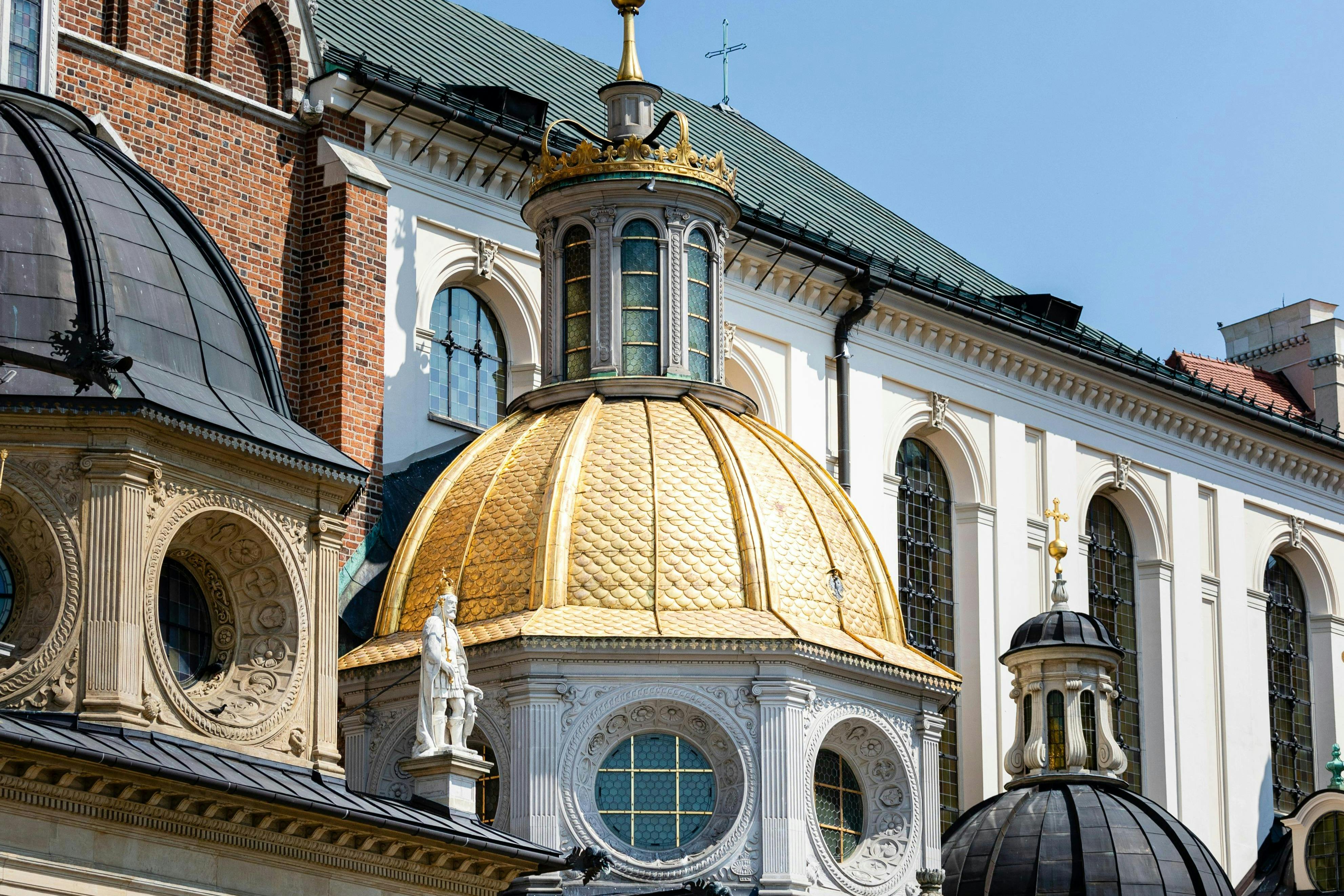A golden-domed building with intricate architectural details and surrounding structures under a clear blue sky.