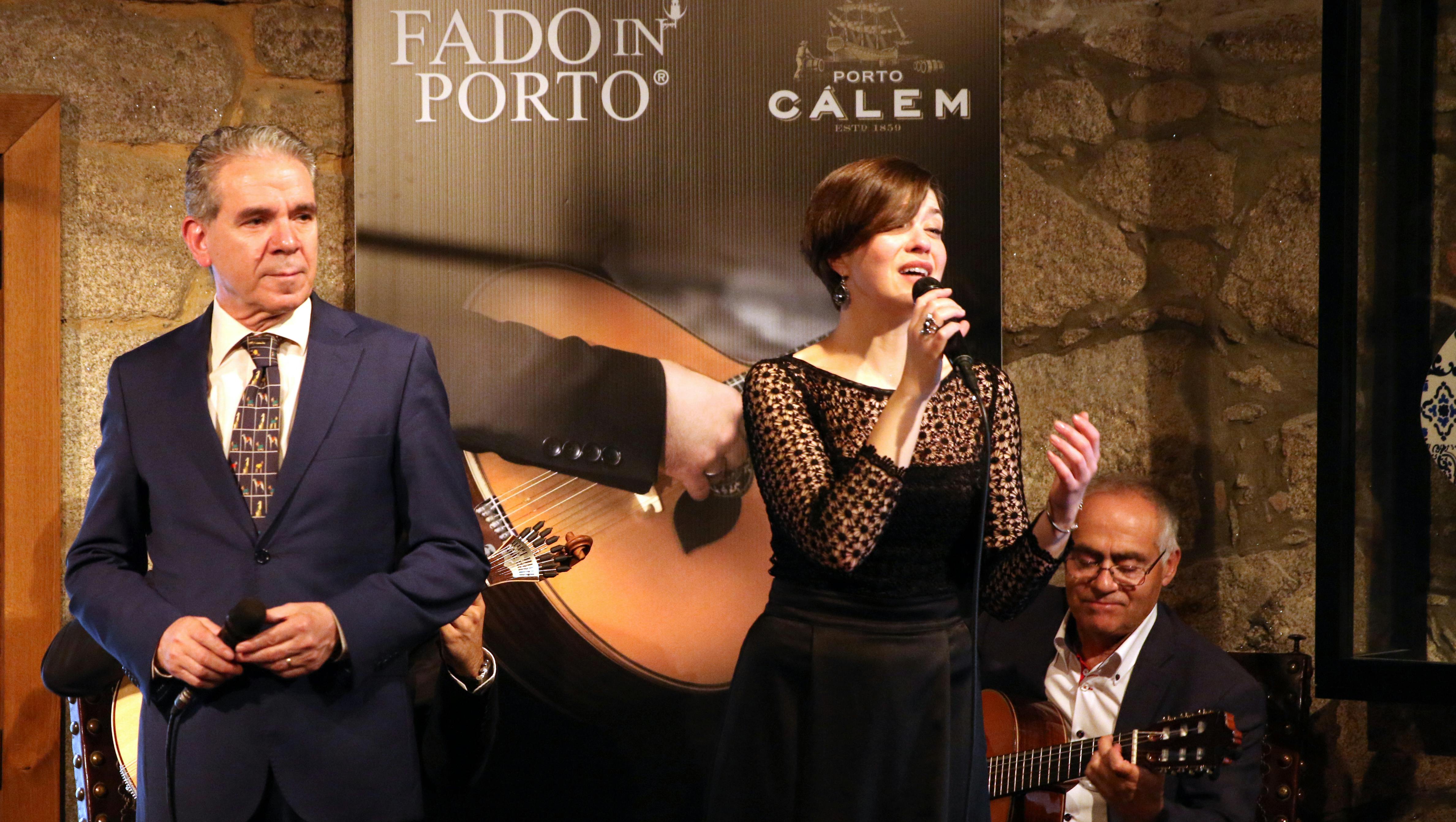 一名女子正在唱歌，一名男子站在她旁边，背景中的海报上写着“波尔图的法多”和“波尔图卡莱姆”。