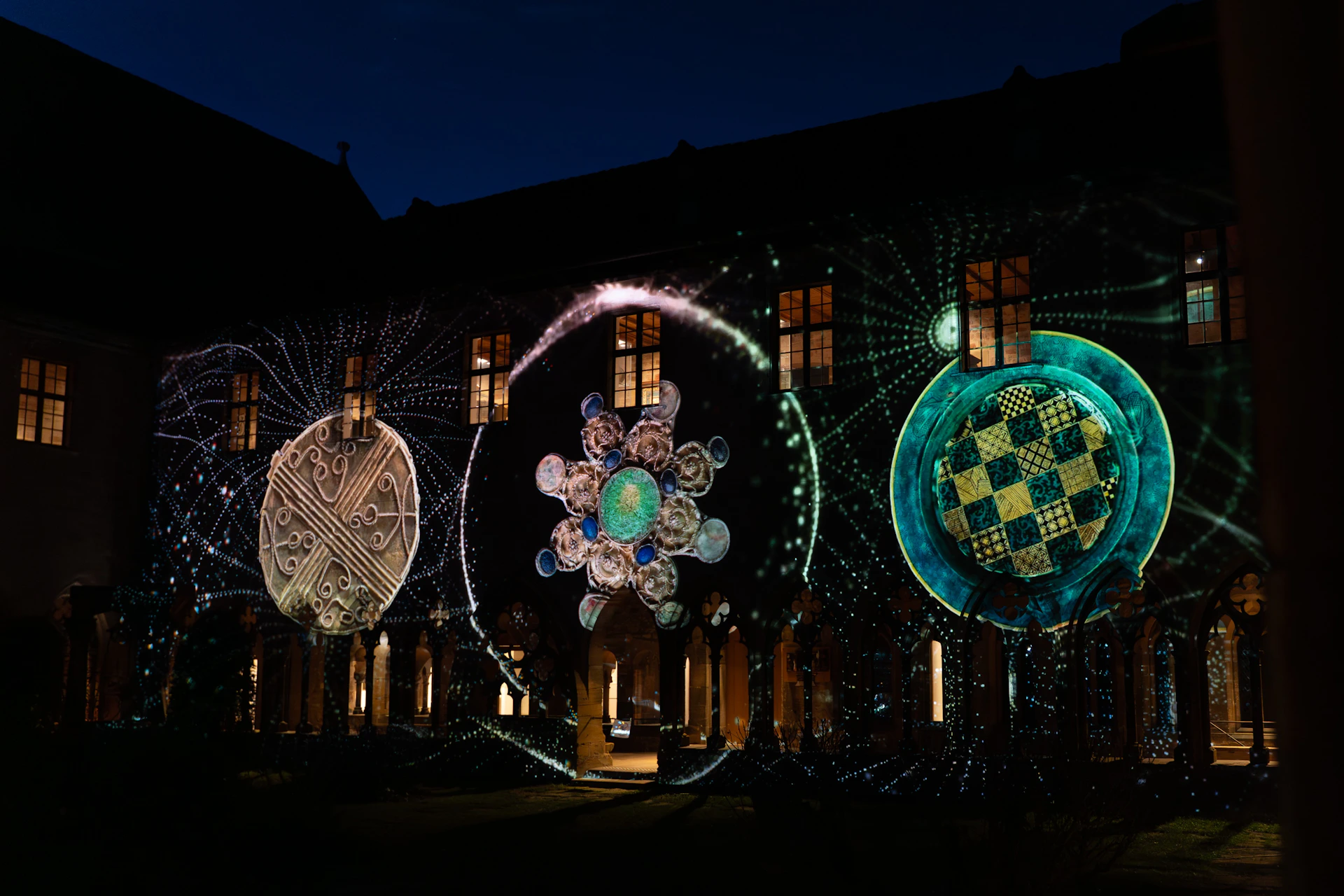 A nighttime scene of an illuminated building facade featuring intricate circular light projections.