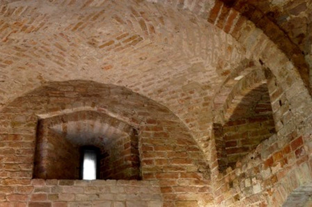 벽돌이 노출된 벽돌 아치형 천장과 좁고 수직인 창문으로 조명이 들어옵니다.