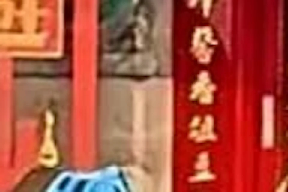 A group of people with bicycles wearing helmets and reflective vests in front of a traditional red Chinese-style building.