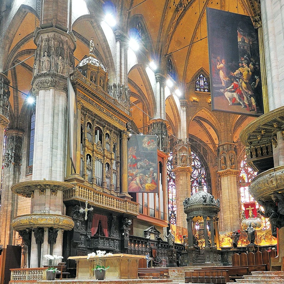 A grand cathedral interior with ornate columns, stained glass windows, religious paintings, and intricate wooden and stone carvings.