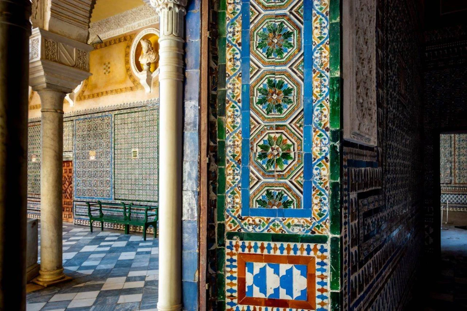 A richly decorated interior with colorful geometric tile patterns, a column, and ornate walls in an architectural setting.
