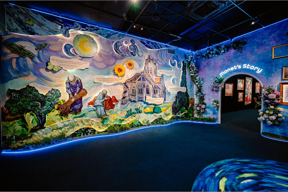 A colorful indoor exhibit with a mural depicting a church and figures, inspired by Van Gogh and Monet's art styles.