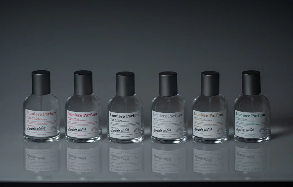 A lineup of six glass perfume bottles labeled 'Lumiere Parfum' with black caps on a reflective surface.