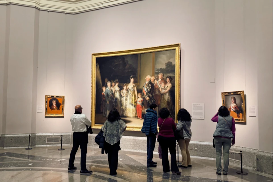 A group of museum-goers stands before Goya’s royal portrait of Charles IV and his family.