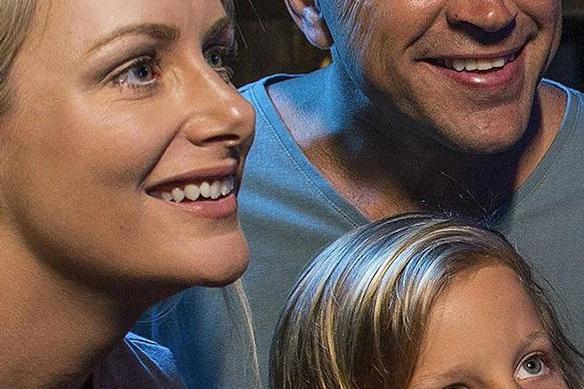 A family of four, two adults and two children, looking excitedly at an octopus in a tank at an aquarium exhibit.